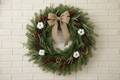 Decorative wreath with a burlap bow, pine cones, and berries on a white background