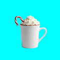 White mug with hot chocolate, whipped cream, and a candy cane on a blue backgroundffff